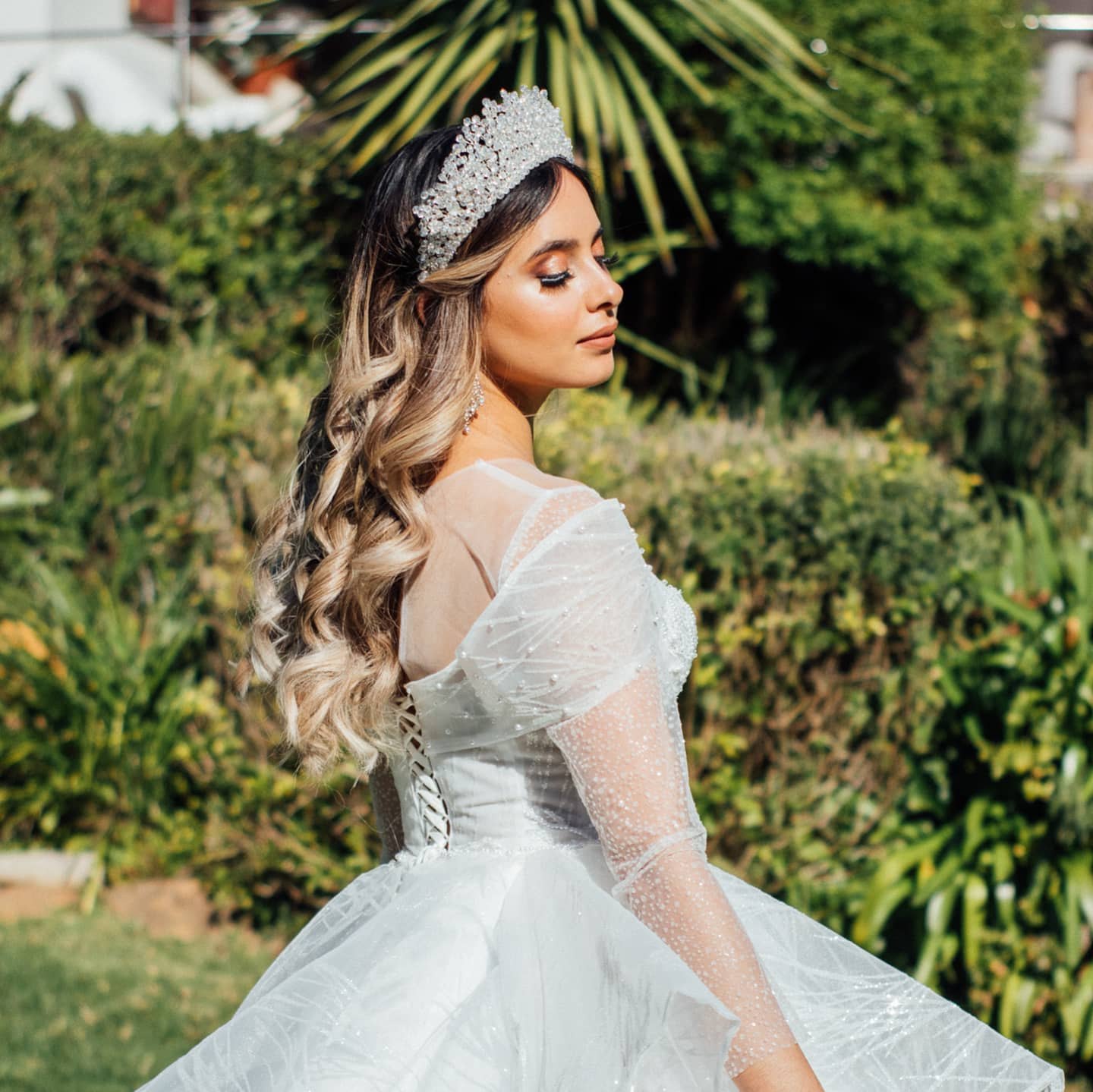 Bride with long, soft waves and a crystal tiara in a garden